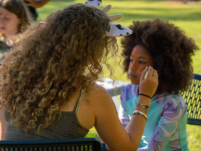 Photo of a camper getting their face painted by a counselor at Camp Coleman